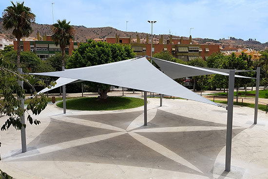 A grey shade structure installations in the middle of a public park square.